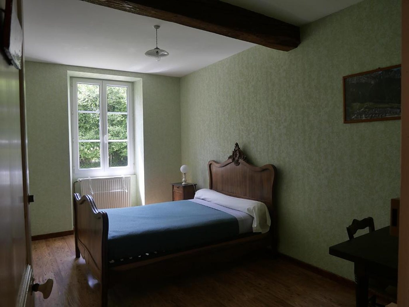 Chambre au papier peint vert avec lit ancien en bois