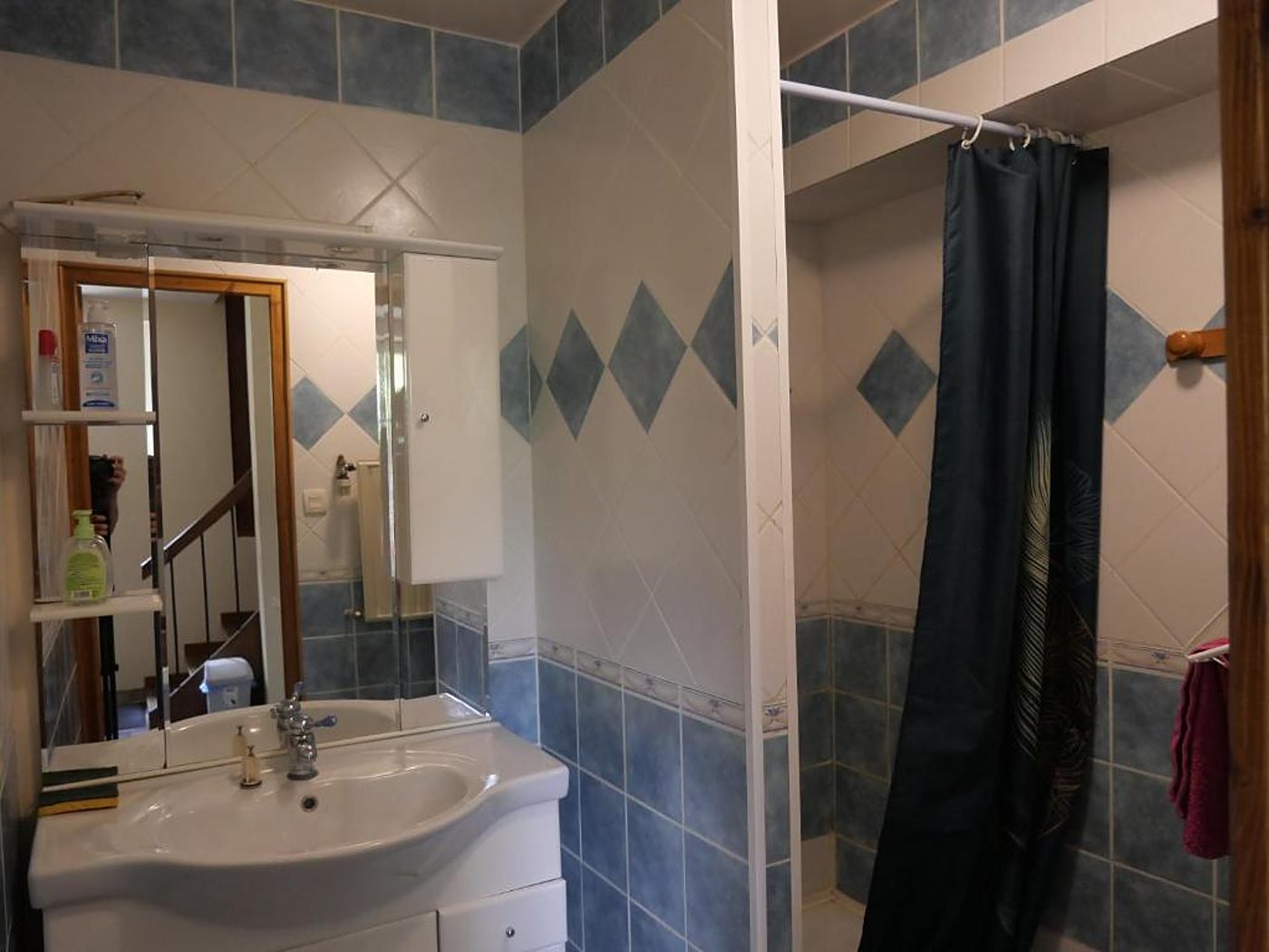 Salle de bain carrelée bleu et blanc avec lavabo et douche